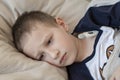 Pre-school sick boy in pyjama lying in bed with a digital thermometer